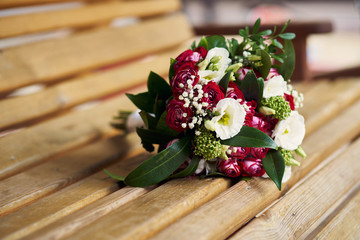 Wedding bouquet on a wooden bench in red colors