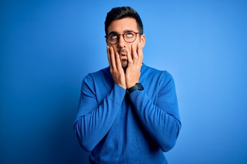 Young handsome man with beard wearing casual sweater and glasses over blue background Tired hands covering face, depression and sadness, upset and irritated for problem