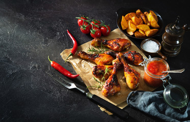 Grilled chicken drumstick served on paper with french fries and sauce