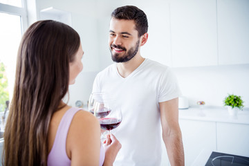 Back rear spine view photo of positive bonding spouses man woman have stay home romantic meal hold glass wine toast clink cheers in kitchen indoors