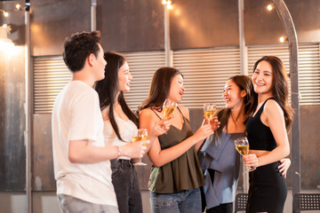 Group of young cute Asian man and woman friends having party at rooftop restaurant. Girls drinking beer alcohol and toasting bottle feeling happy enjoy, fun with smile face. Night lifestyle concept.