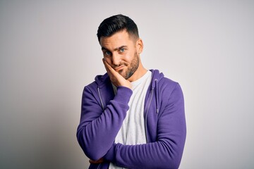 Young handsome man wearing purple sweatshirt standing over isolated white background thinking looking tired and bored with depression problems with crossed arms.