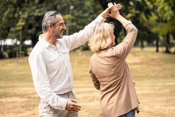 Lifestyle, senior elderly retirement couple dancing together in park. Old man holding woman hip and...