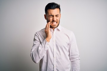 Young handsome man wearing elegant shirt standing over isolated white background touching mouth with hand with painful expression because of toothache or dental illness on teeth. Dentist