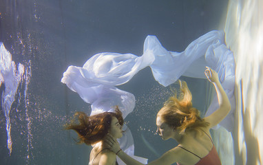 Two beautiful lesbian girls are swimming underwater. Attractiveness. Sexual poses and gestures....
