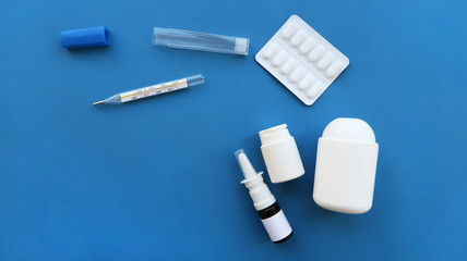 medicine  pills and white bottle, thermometer on blue background. Copy space for text stock photo           