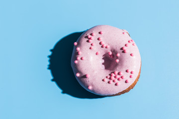 Trendy sunlight. Doughnut on bright light blue turquoise background. Minimal summer concept. Pop art style. Pink donut.