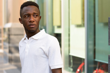 Obraz premium Portrait of young African man thinking and looking back in the city outdoors