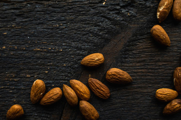 Almonds scattered on the wooden vintage table. Almond is a healthy vegetarian protein nutritious food. Almonds on rustic old wood.