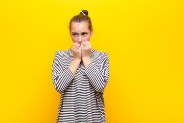 young blonde pretty girl looking worried, anxious, stressed and afraid, biting fingernails and...