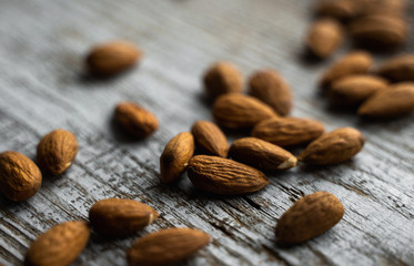 Almonds scattered on the wooden vintage table. Almond is a healthy vegetarian protein nutritious food. Almonds on rustic old wood.