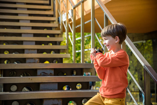 Photo Of The Boy Looking At A Smart Watch. Children And Modern Technology. Kid Calling To His Friends Or Parents After School