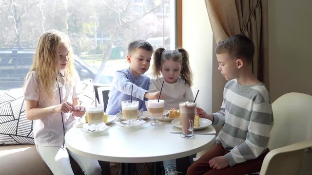 A friendly company of children in cafe with a delicious desserts. The day of the birth
