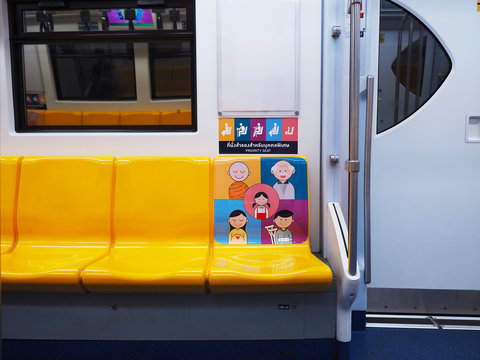 Empty yellow seat with colorful graphic cartoon for priority people on BTS Sky train, Bangkok, Thailand.