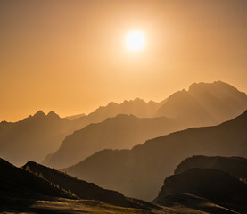 Sun glow in evening hazy sky and mountain silhouettes view
