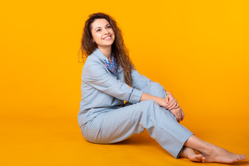 Smiling young girl in pajamas home wear posing while resting at home isolated on yellow background studio portrait. Relax good mood lifestyle concept.