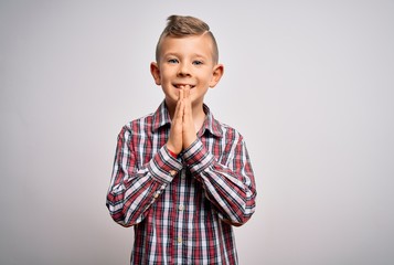 Young little caucasian kid with blue eyes wearing elegant shirt standing over isolated background praying with hands together asking for forgiveness smiling confident.