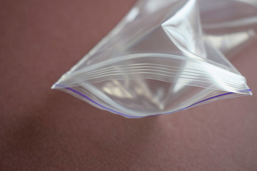 Small transparent plastic bag with zip clasp on a dark background. The clasp is open. © Milya
