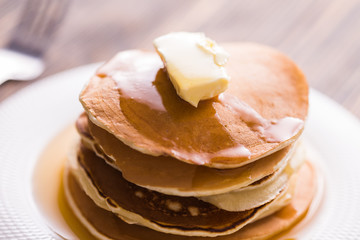 Golden pancakes with butter and warm maple syrup.