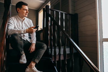 serious young man sitting on the   stairs and look  around 