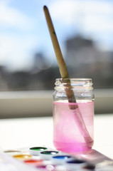 Painting. Drawing by paints. A can of water for washing brushes. Watercolor paints out of focus. Blurred background. Bokeh Window. School of drawing. Copy space.