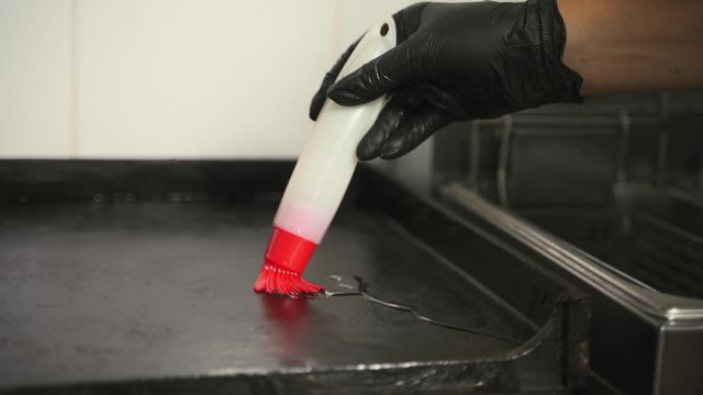 the chef with a brush spreads the pan with sunflower oil