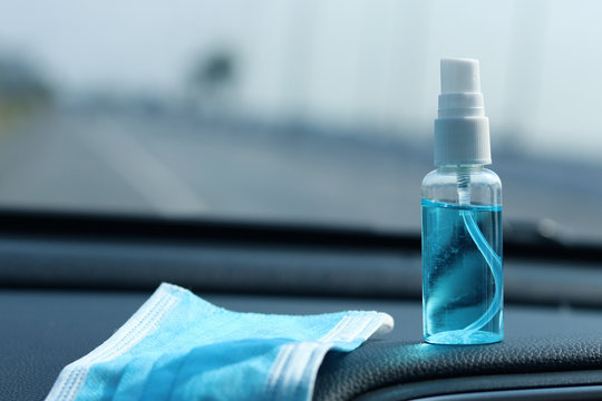 Medical face mask and alcohol based hand sanitizer spray placed on the car console.Concept about new normal,social distancing,business, 
 and travel guideline for prevention of Covid-19 (Coronavirus).