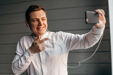 Happy man making facetime video calling with smartphone at home, using zoom meeting online app, social distancing, work remotely concept