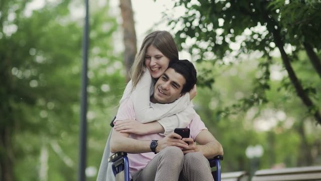 Young disabled man is happy with the hugs of the woman he loves. They go to walk in park