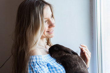 Pet and Easter concept - Attractive girl hugging brown rabbit at home, close-up.