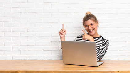 young pretty latin woman smiling happily and pointing to side and upwards with both hands showing...