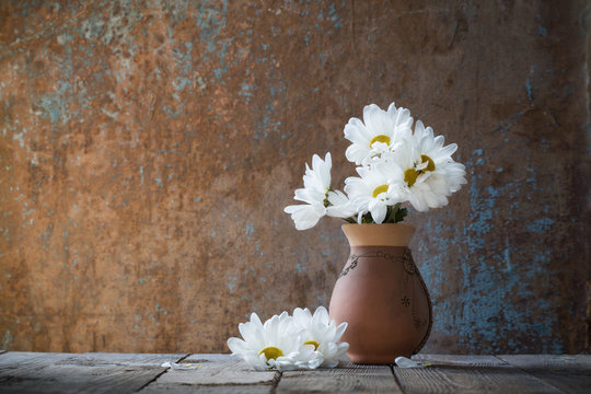 white flowers in jug on old wooden painted background