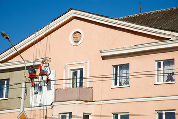 Construction workers hanging on rope and renovating building facade at height. Dangerous and risky job of industrial climbers. Plasterers repairing house facade. Reconstruction of building