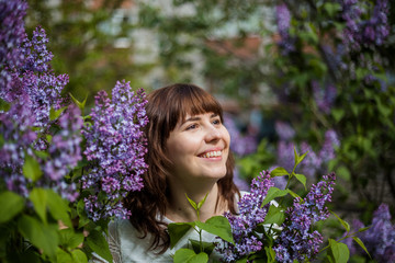 Portrait of a young brunette girl in lilac. The girl in lilac smiles and looks away