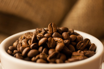A scattering of coffee beans with a cup of coffee.
