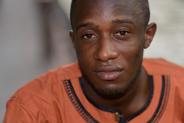 Fototapeta premium Face of young African man with traditional clothes at river in the city