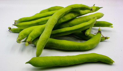 pile of fresh green broad beans in their shells isolated on a white background