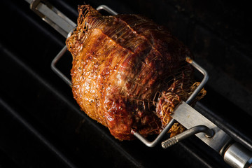 Rolled lamb shoulder on spit on barbecue