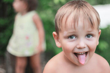 The little Boy Laughs with his tongue out. Baby On A Green Background Of Nature.Outdoor