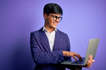 Young handsome business man wearing glasses working using laptop over purple background with a happy face standing and smiling with a confident smile showing teeth