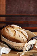 Homemade Freshly Baked Country Bread  in a basket made from wheat and whole grain flour. French Freshly baked bread. Slicing homemade bread. 
