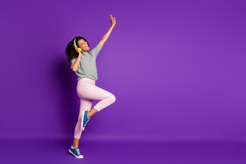 Full length profile side photo of crazy funky afro american girl listen song sue green headset dance sing wear pants pink trousers blue sneakers isolated over purple color background