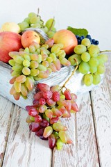 Organic fruits in a wooden crate. Bunches of ripe grapes and apples. Summer fruit harvest