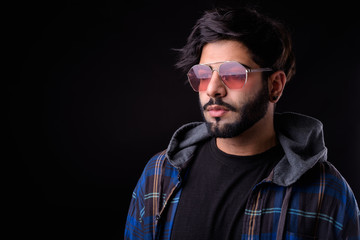 Obraz premium Portrait of young handsome bearded Indian hipster man with sunglasses thinking