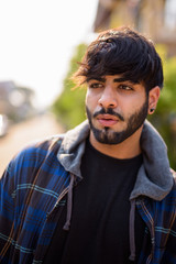 Fototapeta premium Young handsome bearded Indian hipster man thinking in the streets