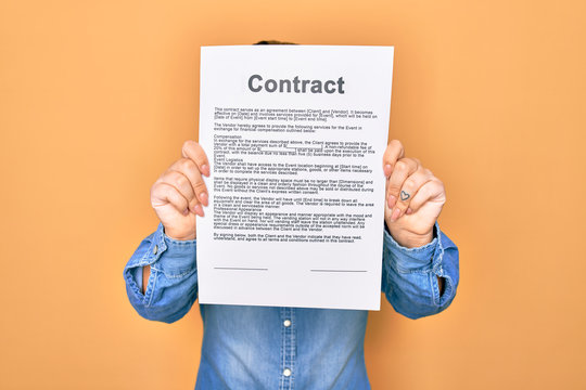 Woman holding contract document paper standing over isolated yellow background