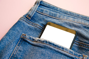 White screen smartphone in jeans pocket. Smartphone place for text. Smartphone in a pocket on a pink background.  Copy Space