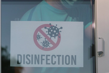 DISINFECTION sign on a door shop or restourant. Store employee attaches a disinfection announcement. Disinfection break during a coronavirus pandemic. Coronavirus disinfection is performed indoors.