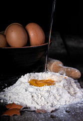 egg falling on flour, bottom bowl with eggs and wooden kneader