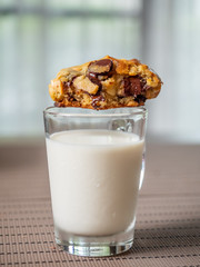 Crunchy chewy chocolate chip soft cookie on cup of milk, selective focus at melting chocolate